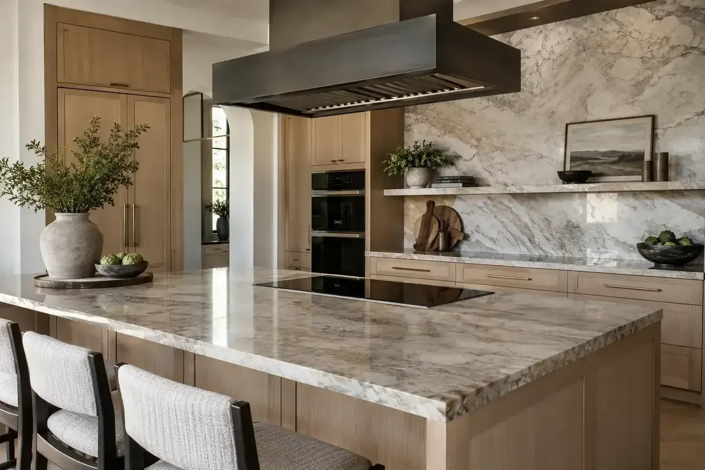 Representative luxury kitchen with a cooktop, ventilation hood, wall ovens, refrigeration, cabinetry, and island seating
