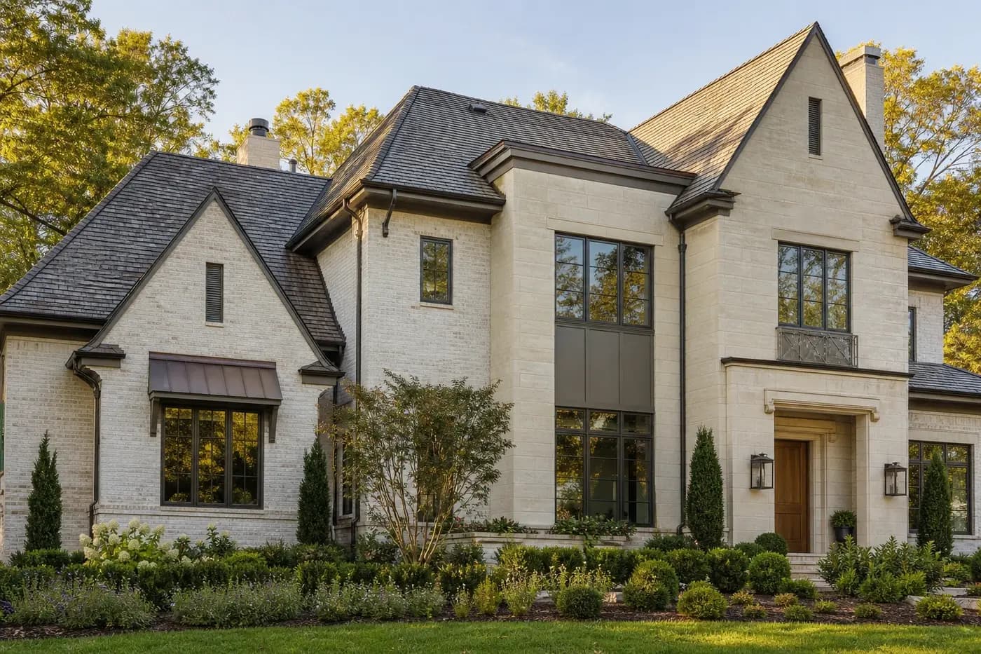 Luxury Charlotte custom home with pale brick, limestone, dark bronze windows, wood entry, and restrained metal accents