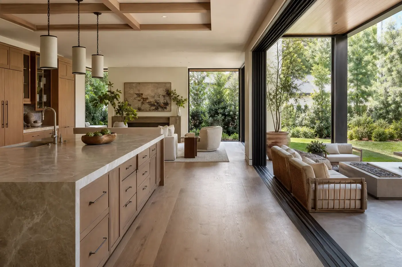 Open luxury kitchen and great room flowing through wide glass doors to a covered garden terrace