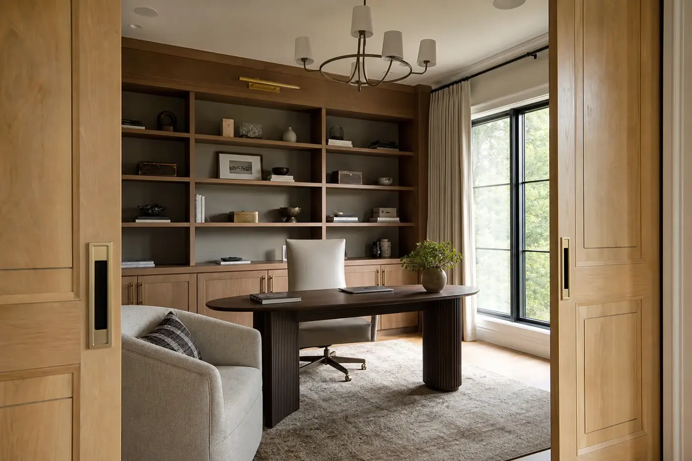 Enclosed white oak library office with pocket doors, layered textiles, and side-window daylight