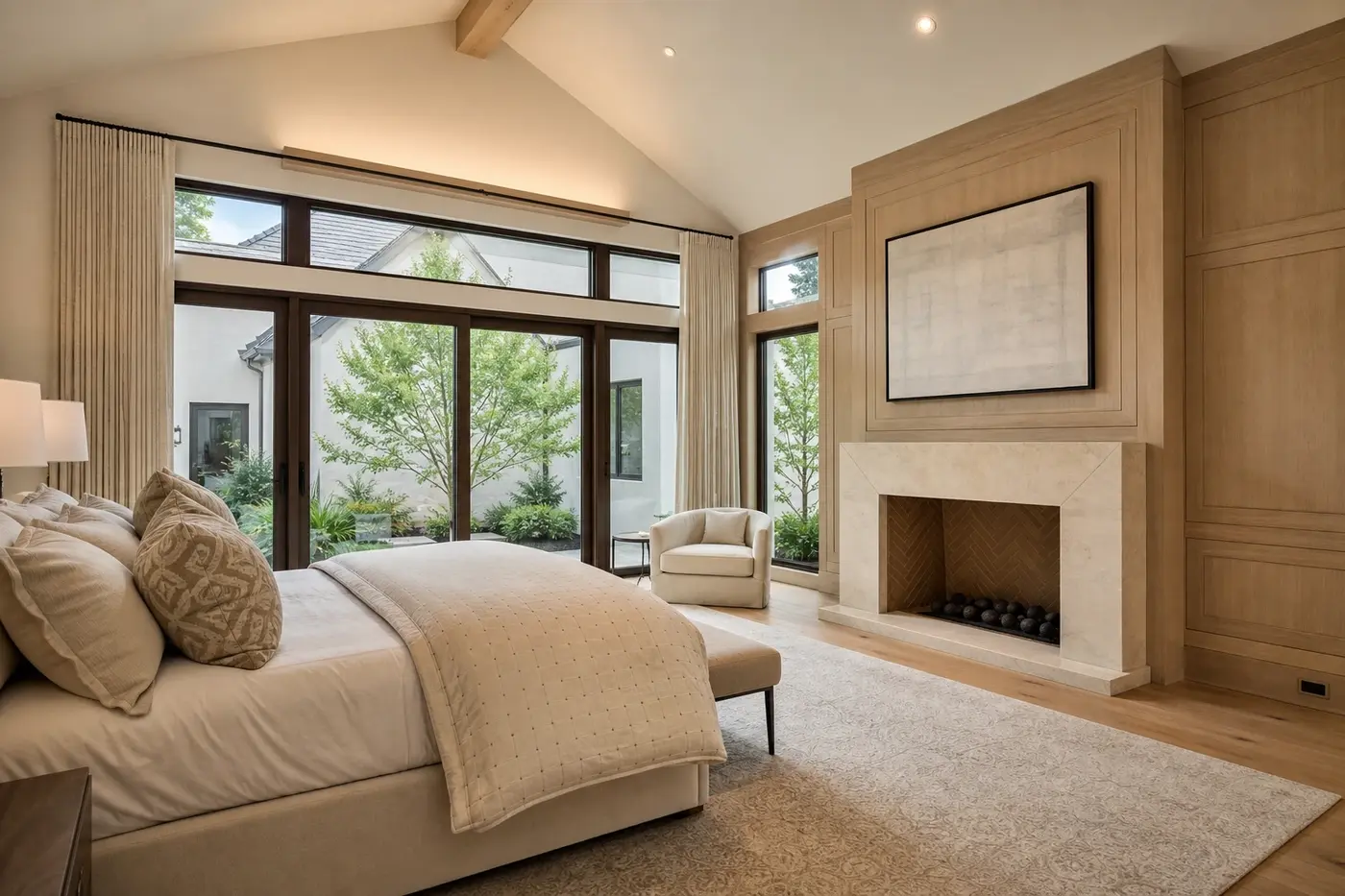 Main-level luxury primary suite opening toward a private planted courtyard in a new custom home