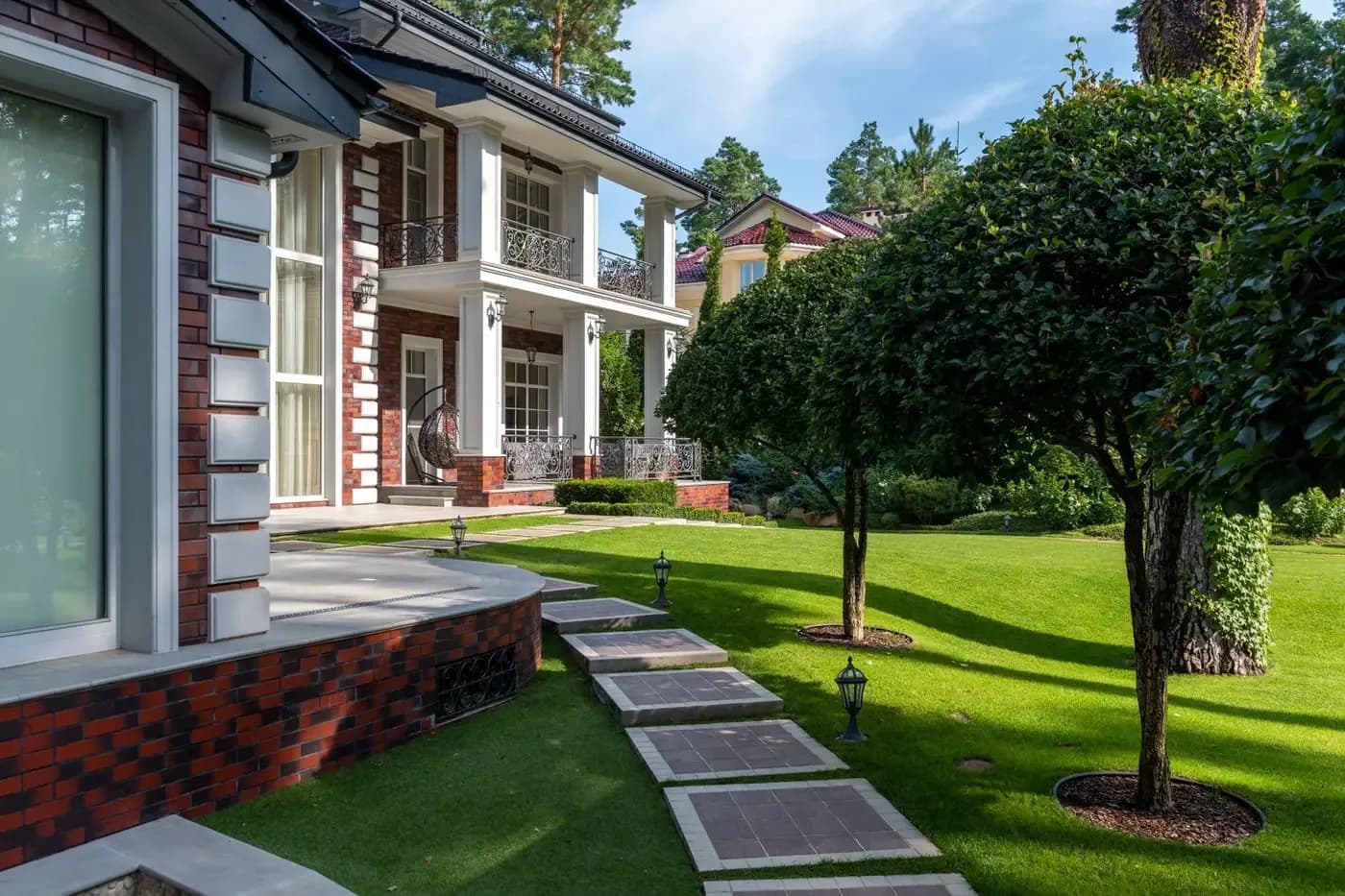 Representative landscaped courtyard with offset residential windows, mature planting, and a clear garden walk