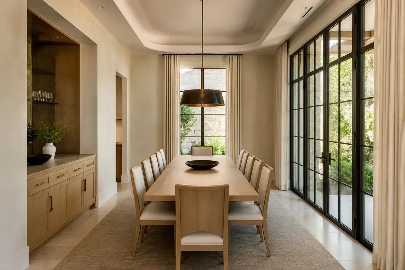 New Charlotte luxury custom-home dining room with a white oak table, garden windows, built-in serving storage, and a centered bronze pendant