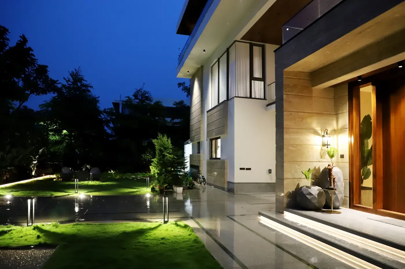 Representative custom home at night with restrained entry, path, and garden lighting