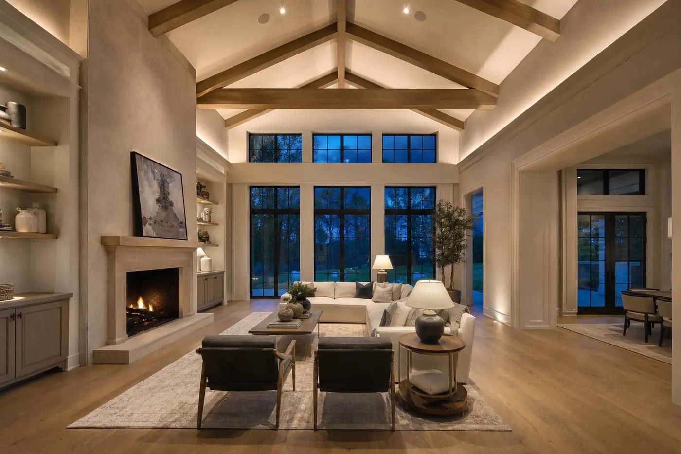 New luxury custom-home great room with a coordinated vaulted white oak ceiling, tall windows, warm layered lighting, and scaled seating