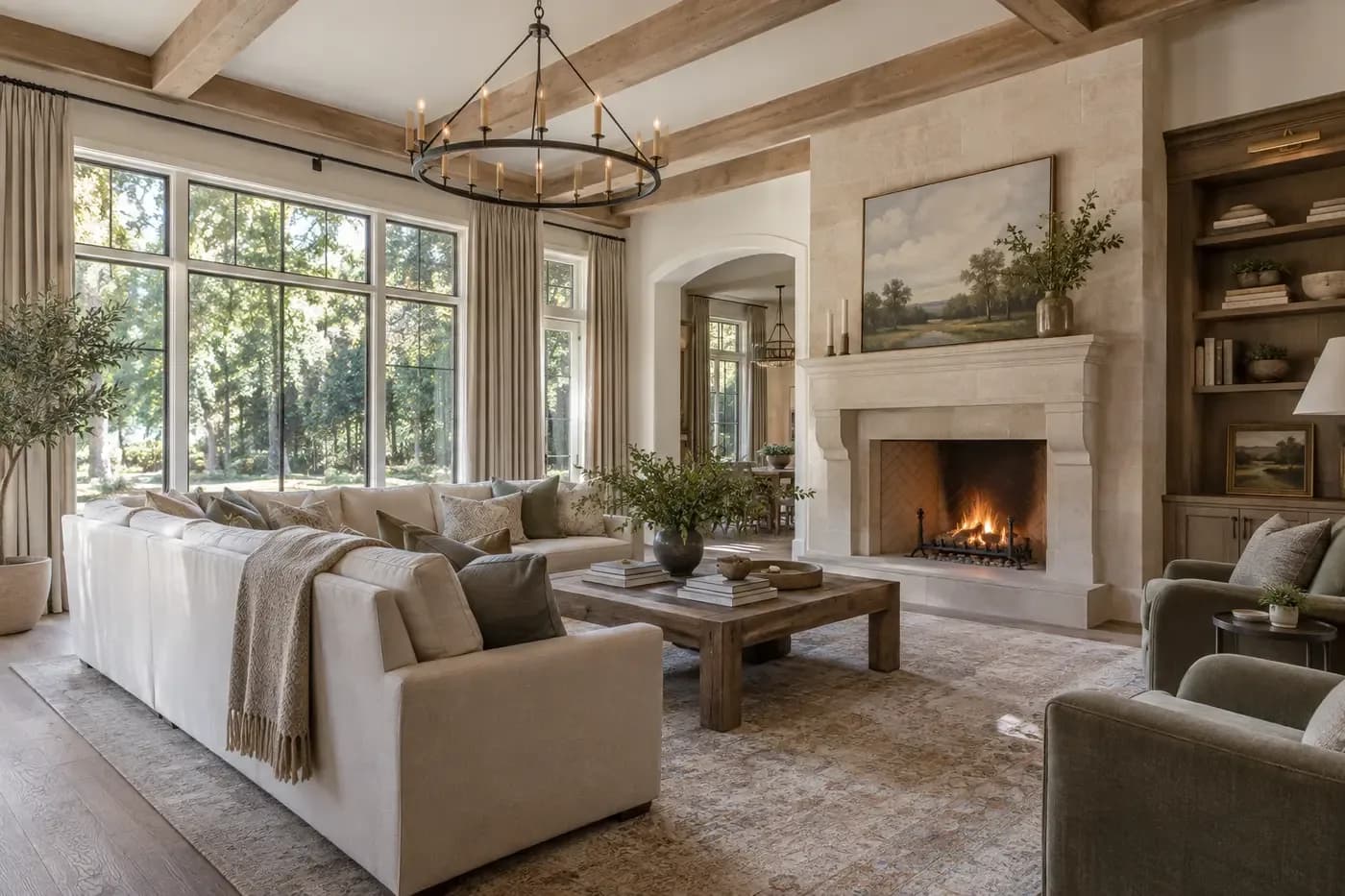 Illustrative luxury custom-home great room with rugs, upholstery, drapery, books, wood beams, and a limestone fireplace