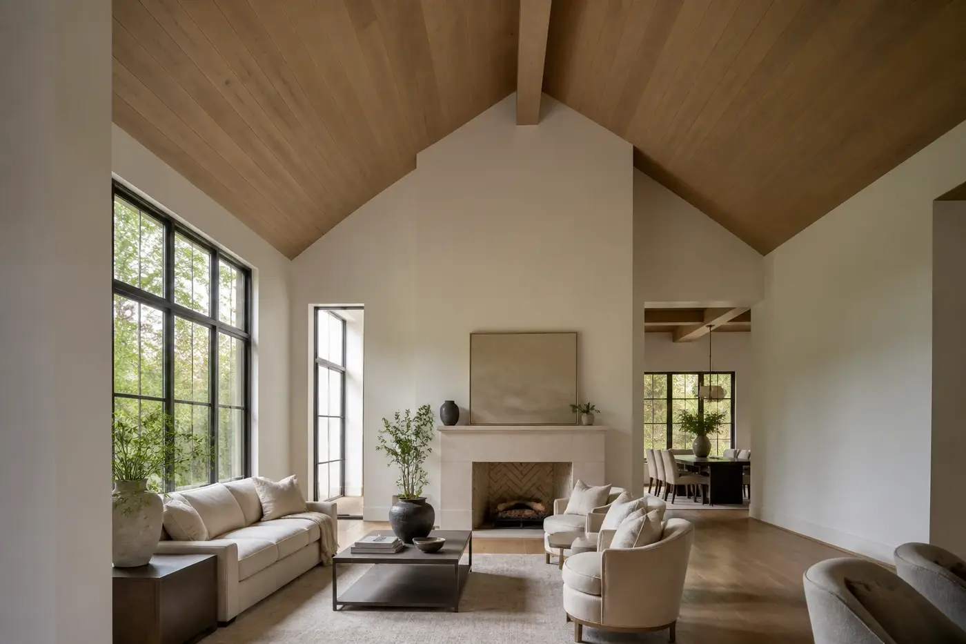 Vaulted great room in a new custom home with a coherent gable ceiling, centered ridge beam, tall windows, and a lower dining transition