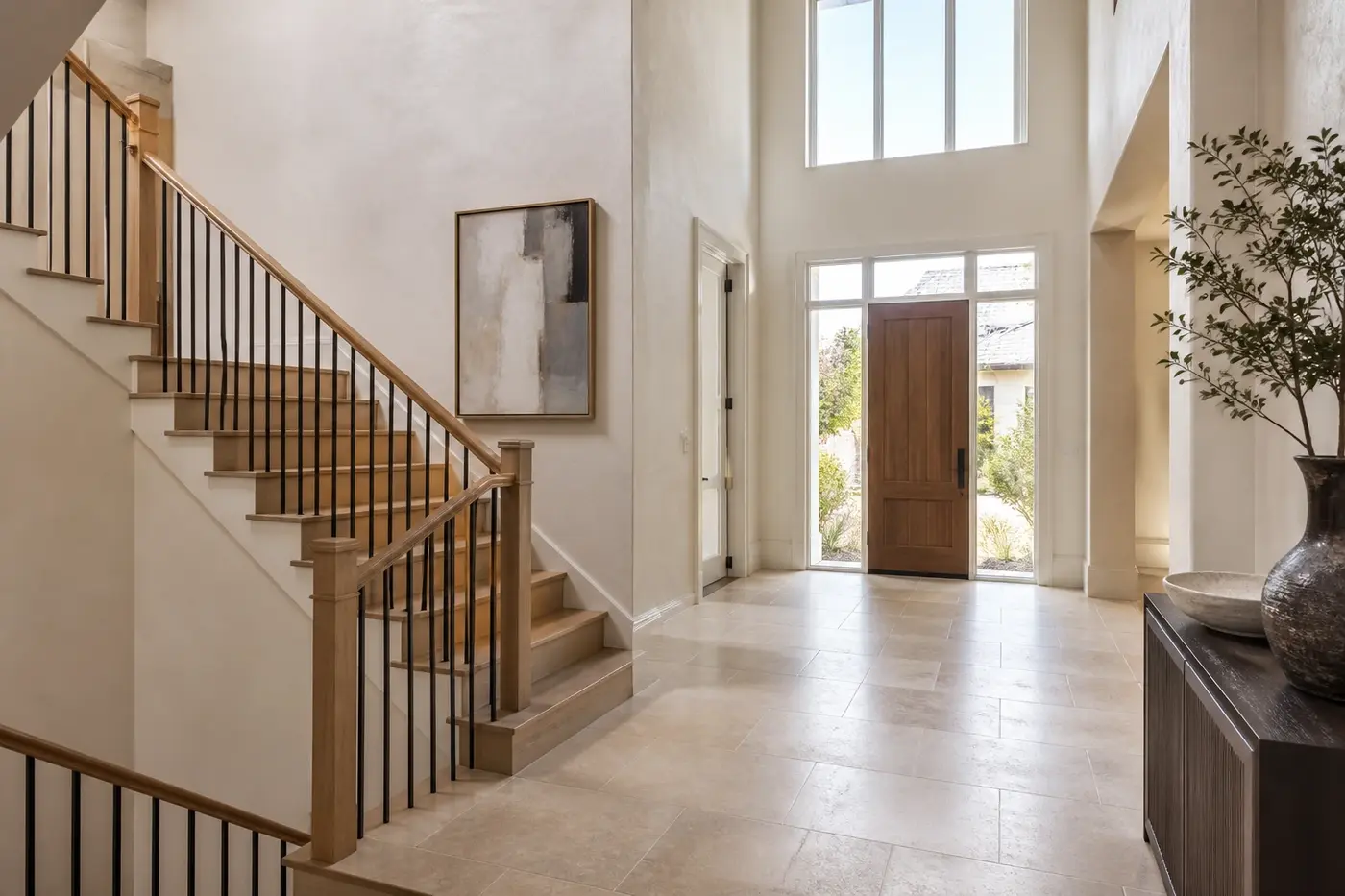 New custom-home foyer with a white oak staircase positioned beside a clear front-door circulation path