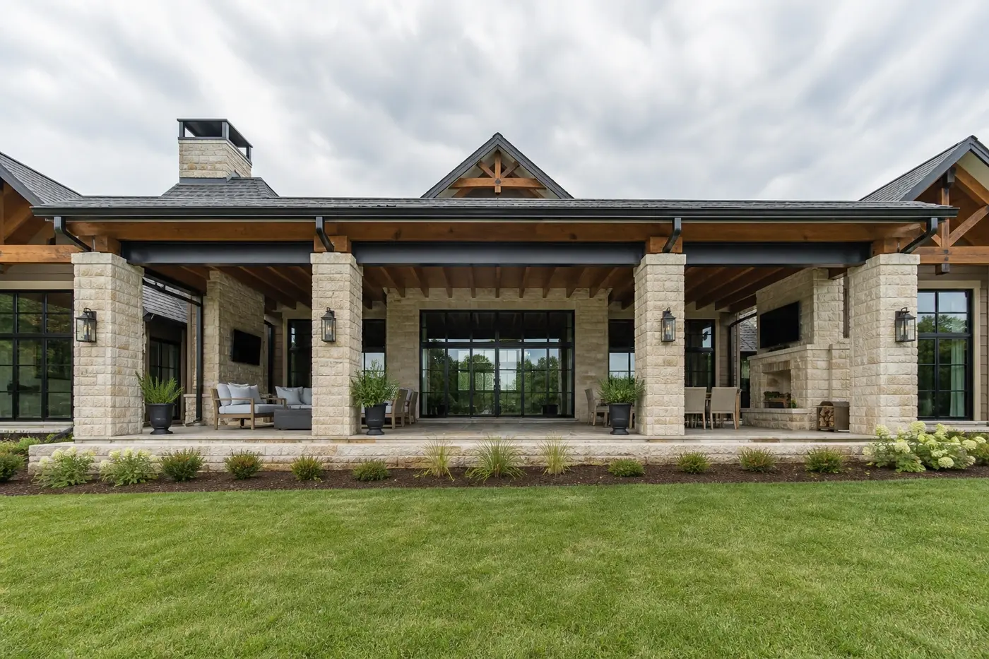 New Charlotte luxury custom-home covered terrace with aligned masonry piers, steel headers, timber rafters, and broad glass doors