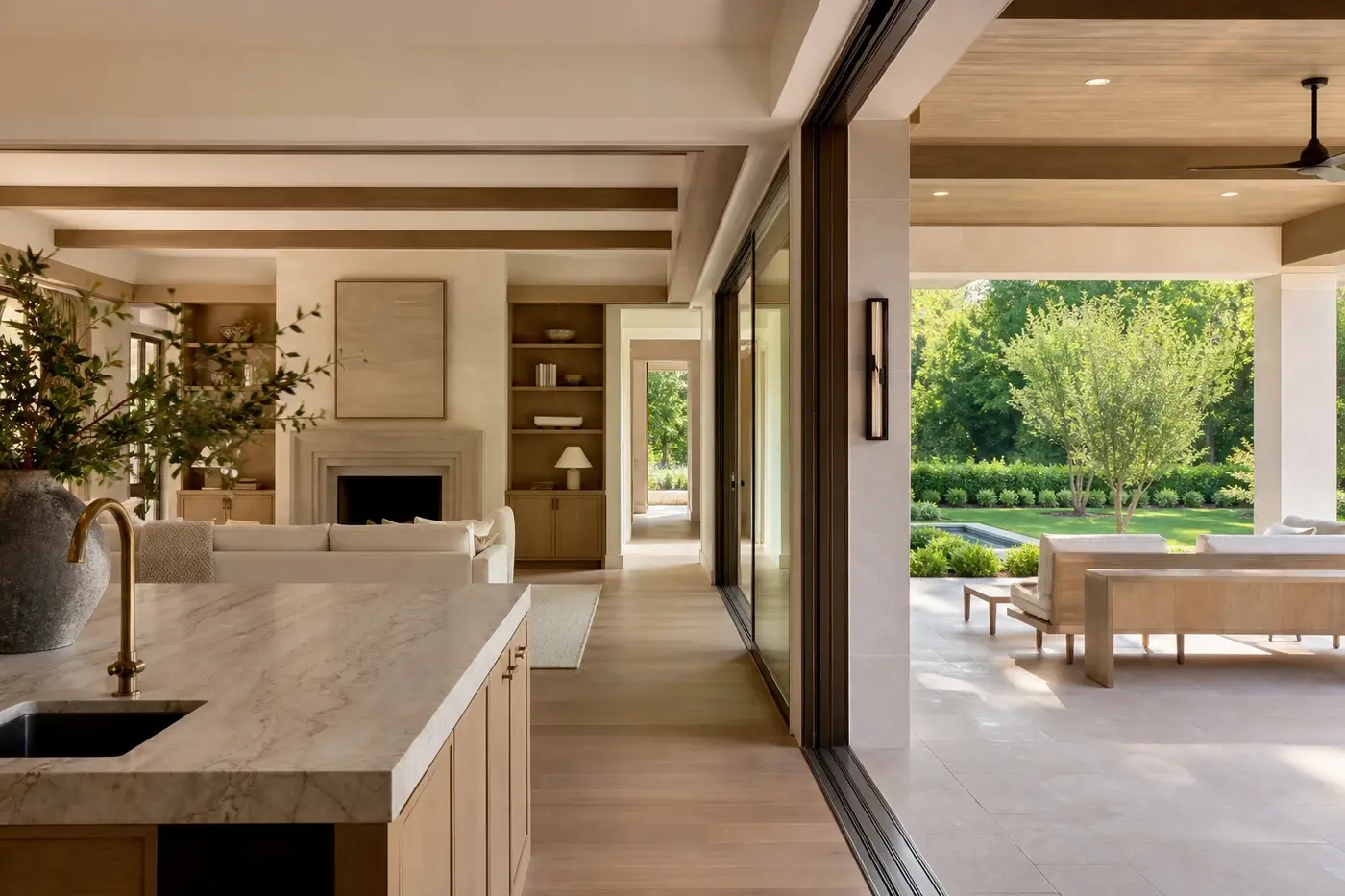 Luxury custom-home kitchen and great room opening across a coordinated glass threshold to a covered outdoor room
