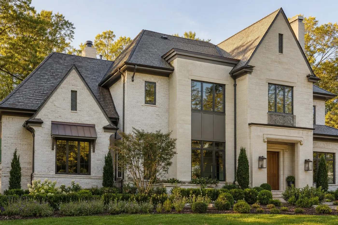 Luxury Charlotte custom home with pale brick, limestone, dark bronze windows, wood entry, and restrained metal accents
